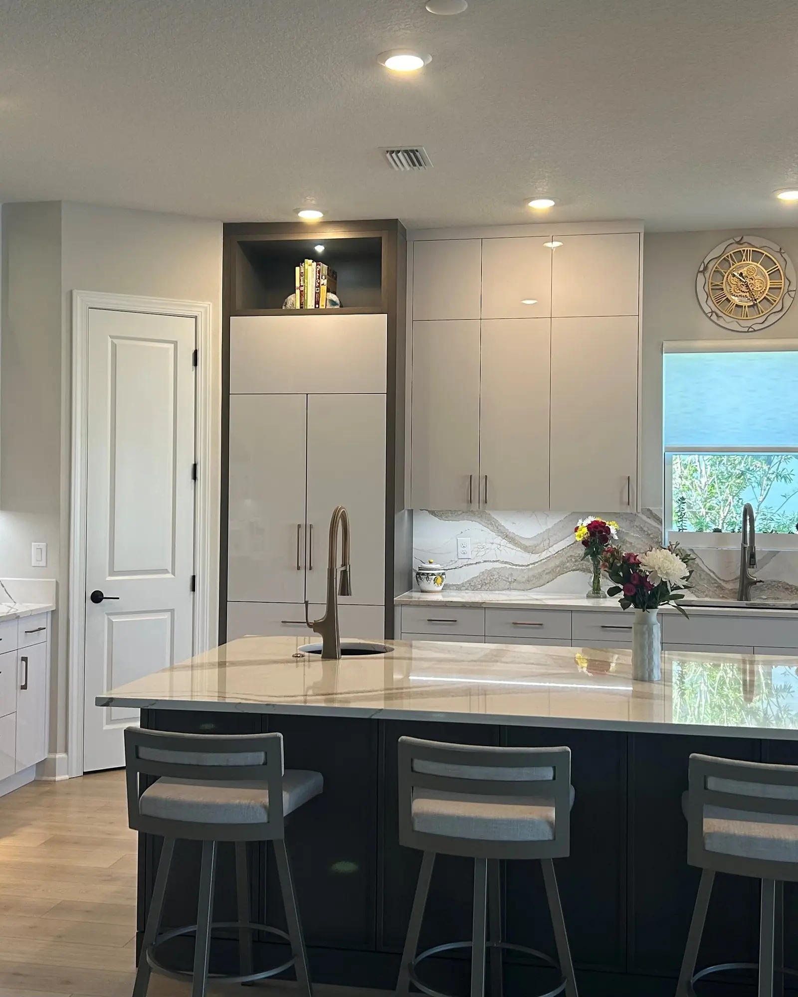 Contemporary kitchen with white custom cabinets and a navy island with seating
