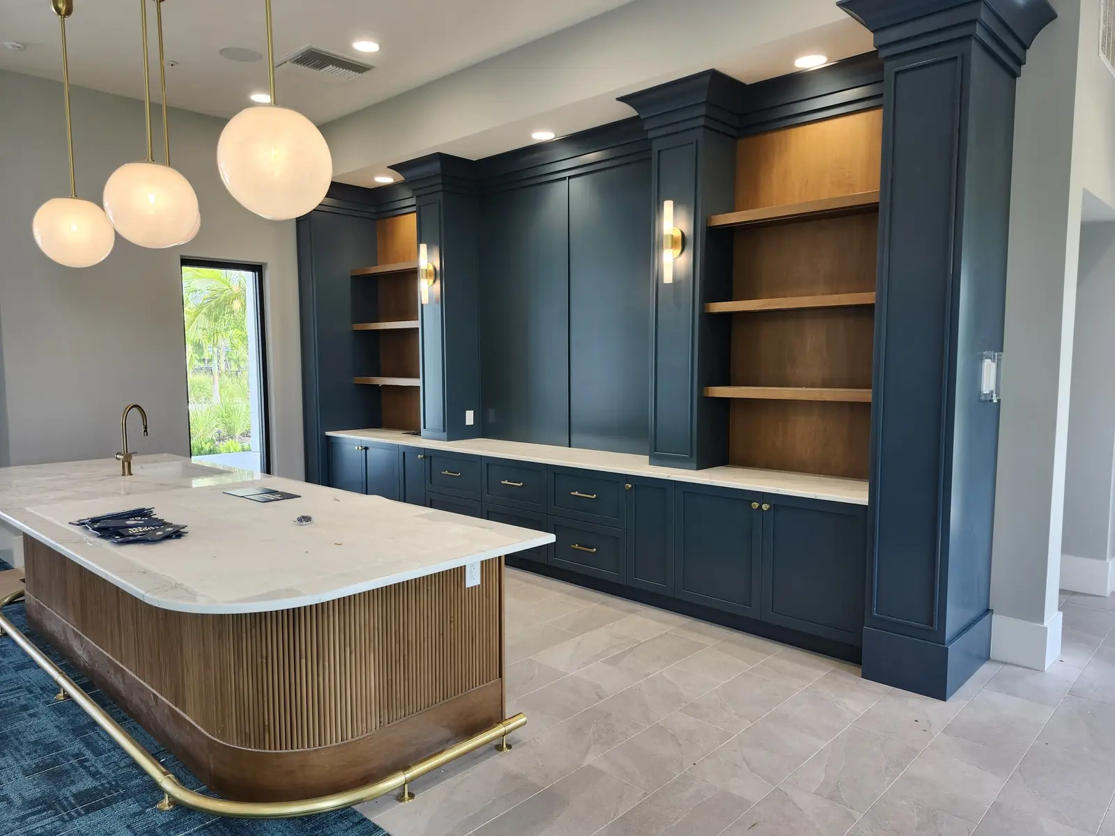 Navy custom built-ins with wood shelving and a curved island