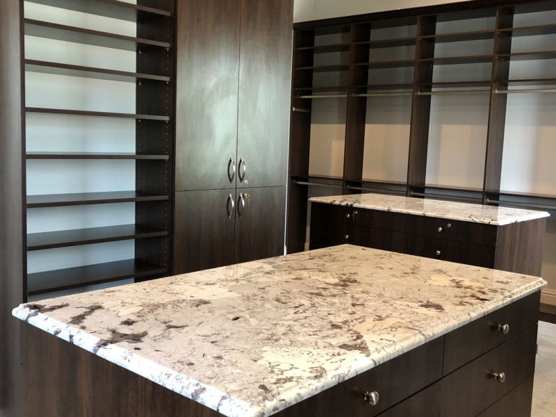 Walk-in closet with dark wood cabinetry and a granite-top center island
