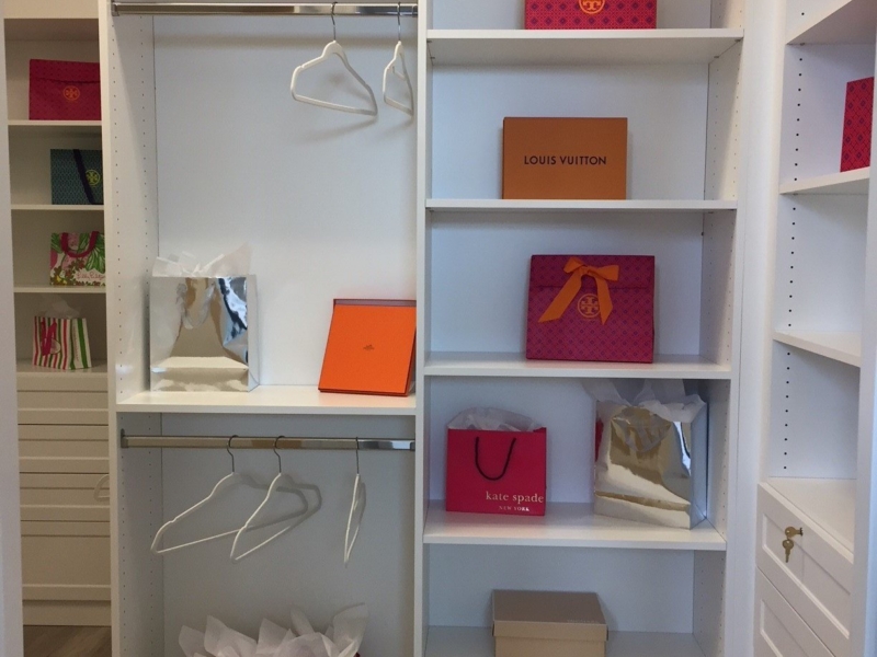 Reach-in closet with white custom shelving and hanging rods