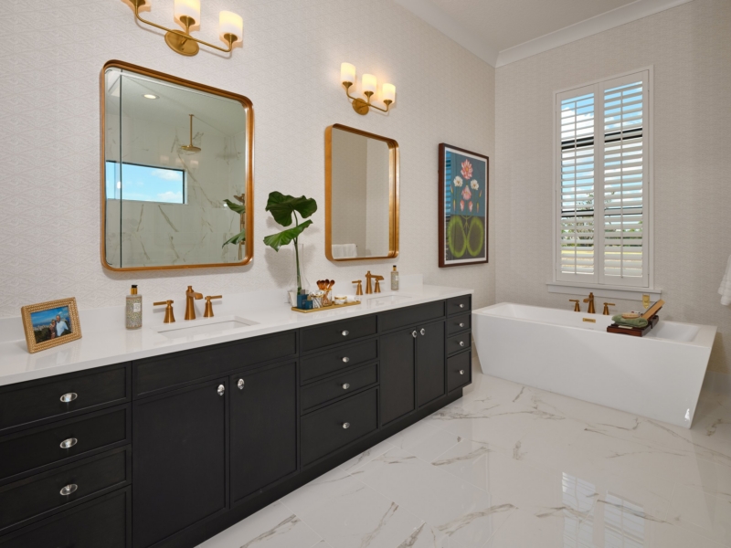 Contemporary bathroom with a black custom vanity and brass mirrors