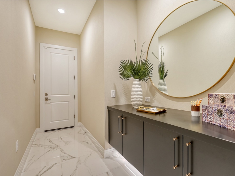 Contemporary bathroom with a dark floating vanity and a round brass mirror