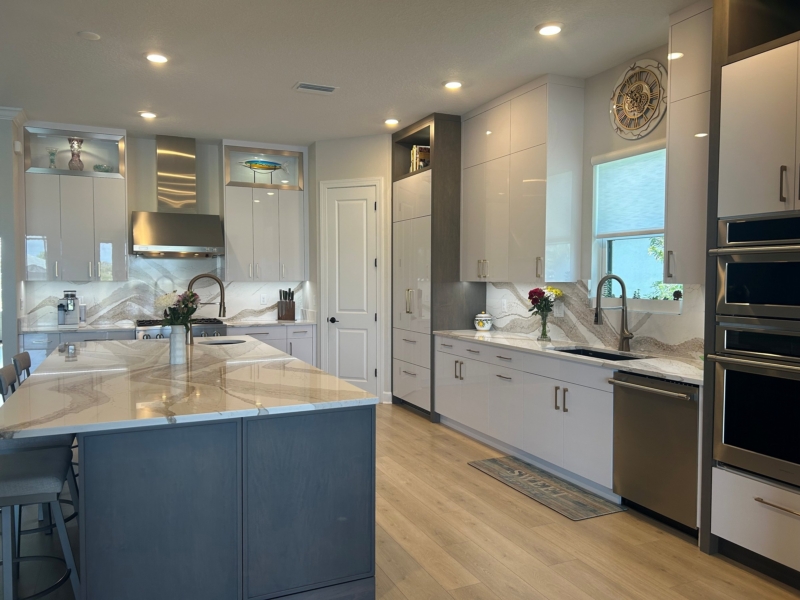 Contemporary kitchen with a navy island, white cabinets, and stacked wall ovens