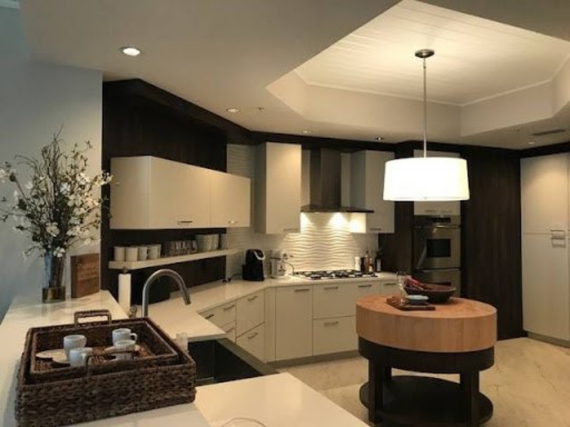 Contemporary kitchen with white and dark wood cabinets and a round butcher-block island