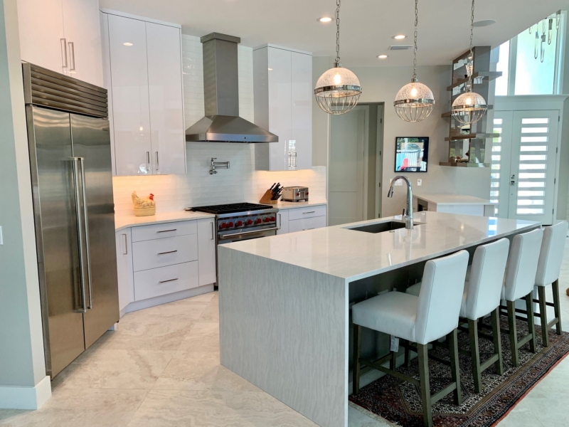 Contemporary kitchen with white high-gloss cabinets, a waterfall island, and globe pendants