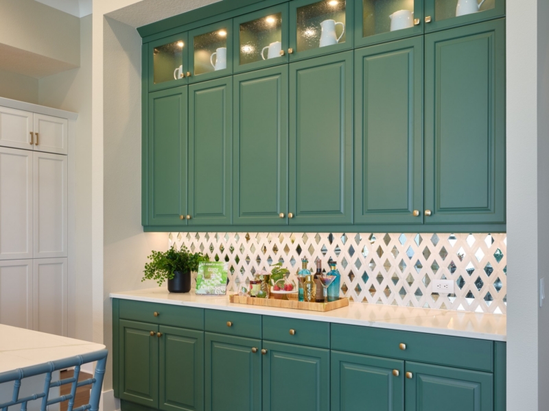 Built-in bar with green cabinets and lighted glass-front uppers