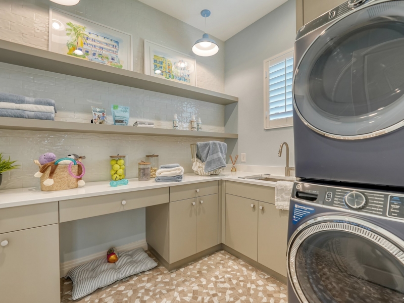 Laundry room with custom cabinets, a built-in desk, and floating shelves