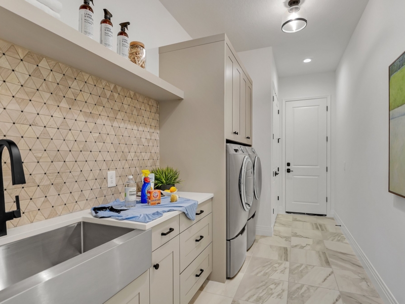 Laundry room with white custom cabinets and a farmhouse sink