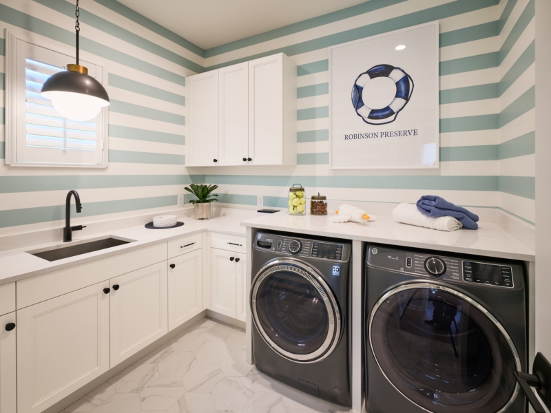 Laundry room with white custom cabinets and a striped accent wall
