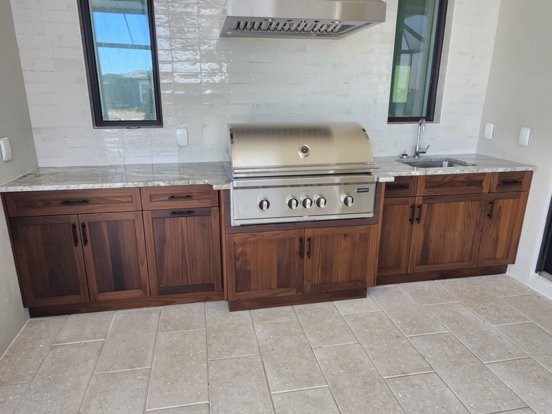Outdoor kitchen with wood custom cabinets and a built-in grill
