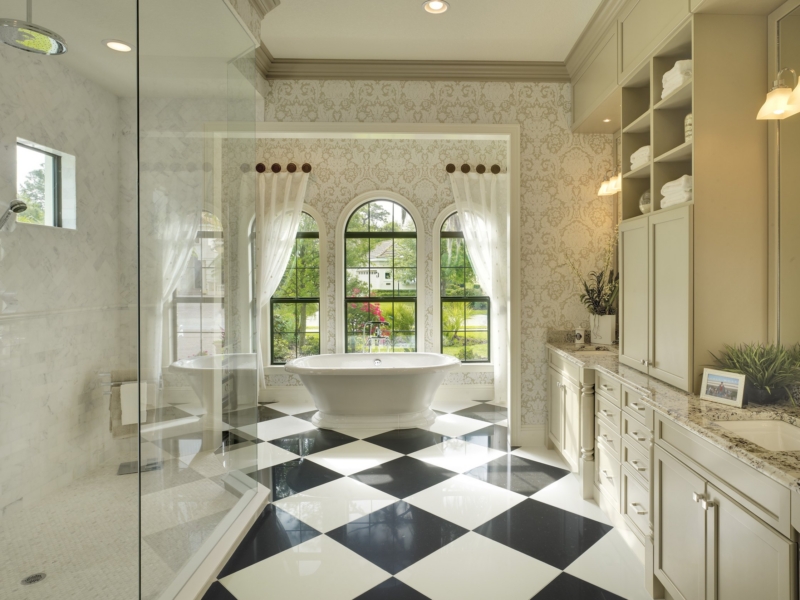 Transitional bathroom with cream vanity cabinets, linen storage, and a freestanding tub