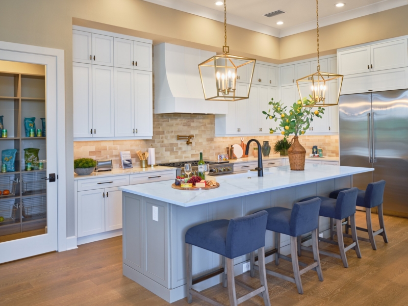 Transitional kitchen with white cabinets, a light blue island, and brass lantern pendants