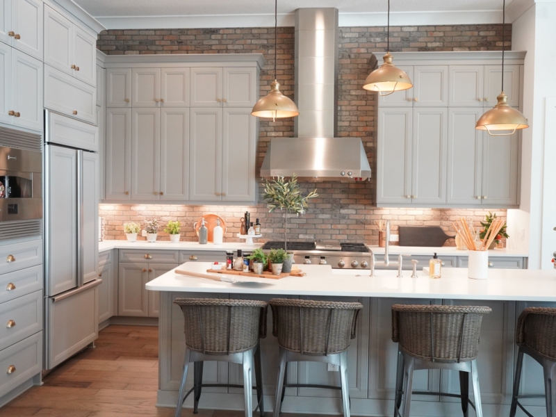 Transitional kitchen with white cabinets, a brick accent wall, and copper pendants