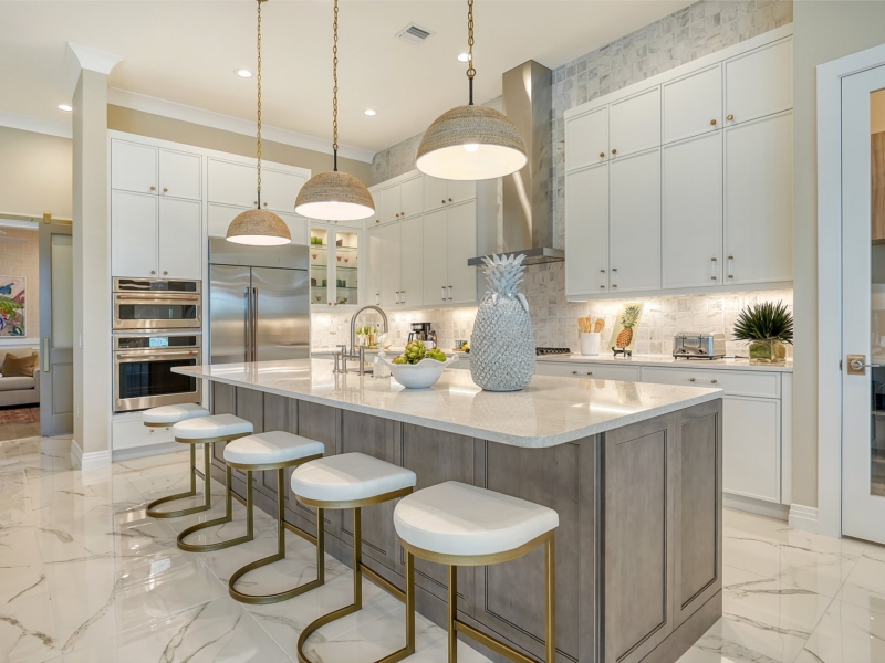 Transitional kitchen with white custom cabinets, a gray island, and pendant lights