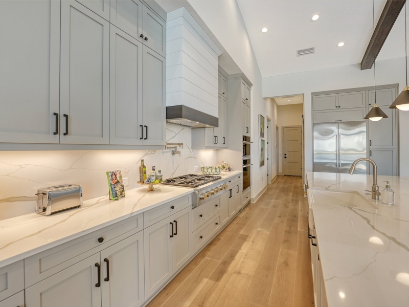 Transitional kitchen with light gray shaker cabinets and a long marble-look island