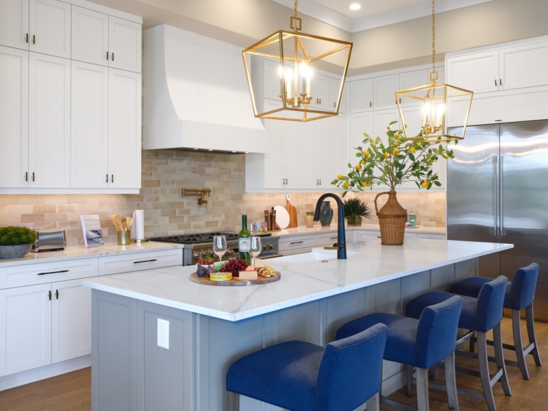 Transitional kitchen island with blue stools under brass lantern pendants