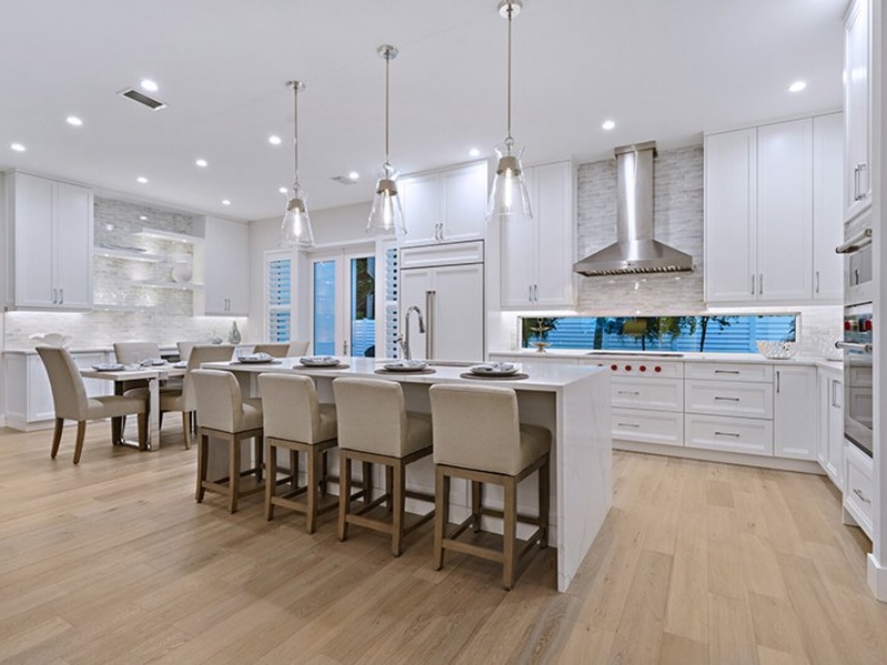 Open transitional kitchen with white cabinets, island seating, and glass pendants