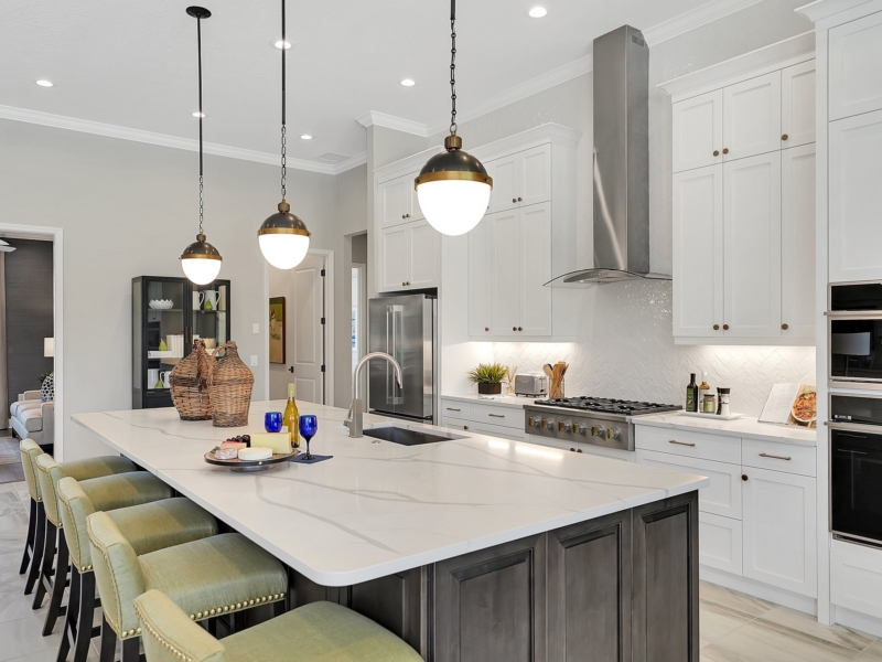 Transitional kitchen with white cabinets, a stained wood island, and globe pendants