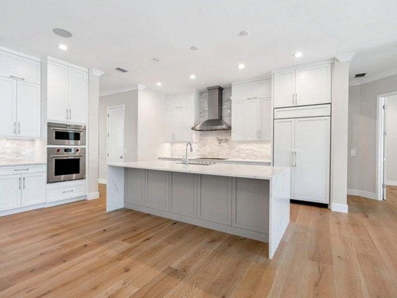 White transitional kitchen with a gray island and a stainless range hood