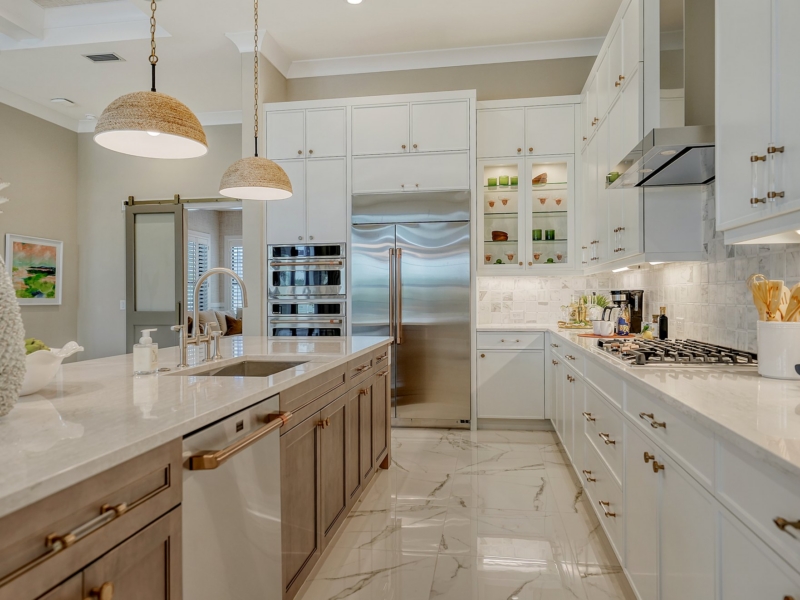 Transitional kitchen with white cabinets, a wood-tone island, and woven pendants